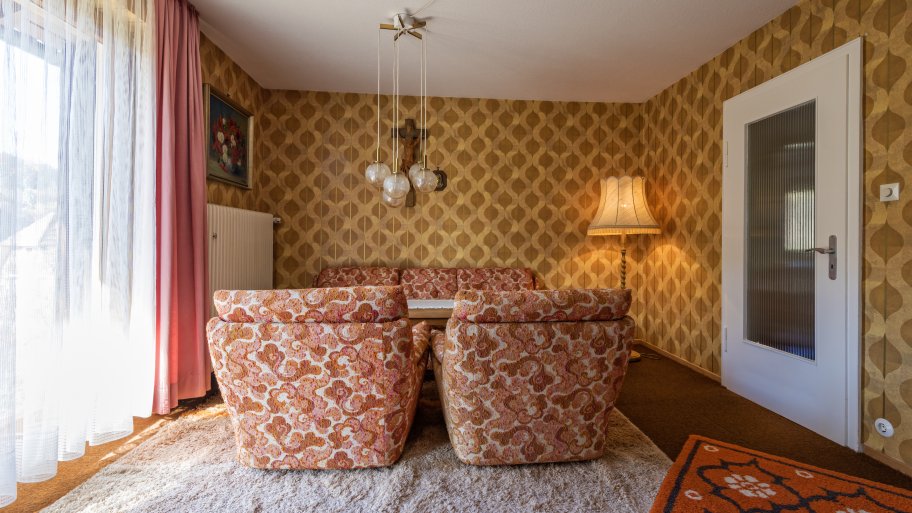 ’70s living room with orange paisley chairs and orange and brown wallpaper